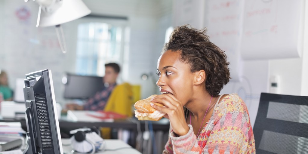 Businesswoman eating burger at desk